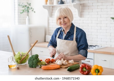 Senior aged old caucasian woman grandmother cutting vegetables for salad. Cooking and home concept, active seniors, healthy eating, fresh ingredients