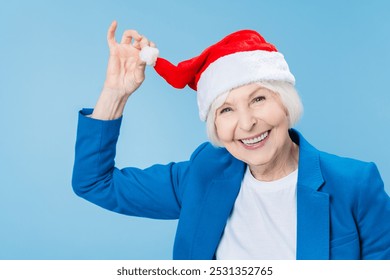 Senior aged woman wearing Christmas santa hat over isolated blue background. Happy New Year and Merry Christmas! Celebration, winter holiday concept - Powered by Shutterstock