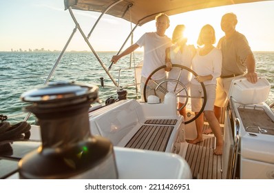 Senior American friends steering private yacht enjoying carefree retirement and embarking on fun travel adventures at sunset