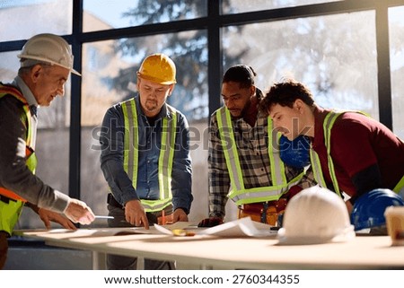 Senior architect and group of workers analyzing building plans at construction site. 