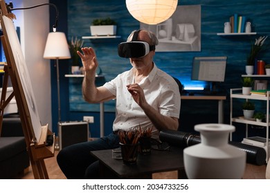 Senior Artist Using Vr Glasses For Virtual Inspiration At Art Studio. Caucasian Old Person With Technology Working On Professional Masterpiece With Modern Headset In Workshop Room