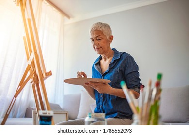 Senior Artist Woman Drawing At Home. Senior Female Artist Working On A Painting. Senior Woman Artist Enjoying Her Hobby At Home. Creative Mature Woman