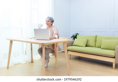 Senior Asia woman is drinking coffee and working from home. - Powered by Shutterstock