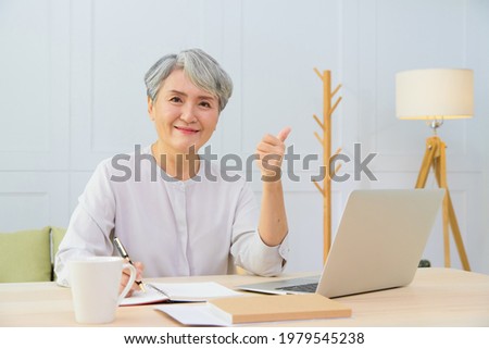 Senior Asia woman working from home using laptop and smart phone. Old woman living and learning online.