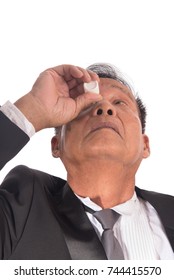 Senior Asian Businessman Getting The Medicine In The Eye. Older Man Applying Eye Drops Isolated On White Background.  Man Has A Cataract In His  Eyes. Health Care Concept.