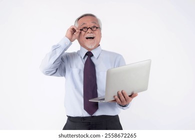 Senior Asian businessman smiling with excitement while holding a laptop and adjusting glasses, standing isolated on white background, concept of technology, success, and modern work lifestyle - Powered by Shutterstock