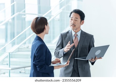 senior asian businessman talking in office corridor,
using laptop. - Powered by Shutterstock