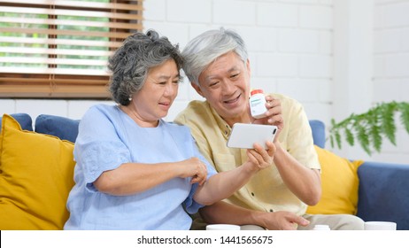 Senior Asian Couple Holding Bottle Of Pill Make Video Conference Call To Doctor, Pharmacy Consulting About Medical Health Care For Retirement, Old People, Elderly And Technology For Health Concept