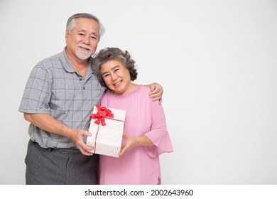 Senior Asian couple holding gift box with ribbon bow isolated on white background, Elderly Asian couple on valentine's day concept - Powered by Shutterstock