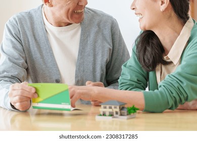 senior asian couple looking at saving account passbook,
						real estate and money concept image.