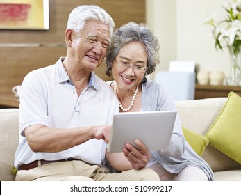 Senior Asian Couple Sharing A Tablet Computer At Home