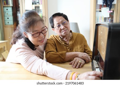 The Senior Asian Couple Trying To Listen Music From The Vintage Radio.