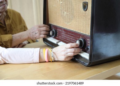 The Senior Asian Couple Trying To Listen Music From The Vintage Radio.