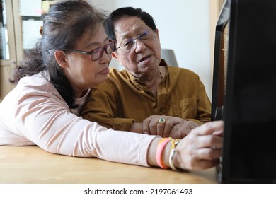 The Senior Asian Couple Trying To Listen Music From The Vintage Radio.