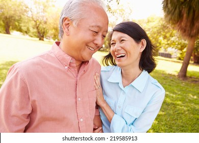 Senior Asian Couple Walking Through Park Together