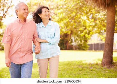 Senior Asian Couple Walking Through Park Together