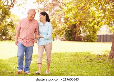 Senior Asian Couple Walking Through Park Together