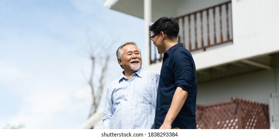 Senior Asian Father With Adult Grown Son Hugging Outdoors.