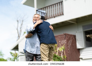 Senior Asian Father With Adult Grown Son Hugging Outdoors.