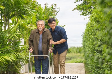 Senior Asian Father And Middle-aged Son Walk In The Park, Man Caregiver Helping Patient, Happiness Asian Family Concepts