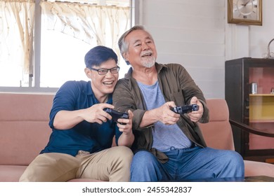 Senior Asian father and middle-aged son playing video game together in living room, Happiness Asia family concepts - Powered by Shutterstock