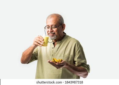 Senior Asian Indian Man Holding Or Drinking Turmeric Milk In A Glass -Healthy Eating Concept