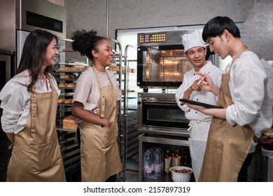 Senior Asian male chef of culinary learning course teaches and explains about electric oven to cooking class students for baking pastry dough for bread and bakery foods in stainless steel kitchen. - Powered by Shutterstock