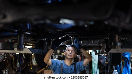 senior asian male mechanic engineering working under Vehicle in Car Service. Repair specialist, technical maintenance. Small business owner. - Powered by Shutterstock