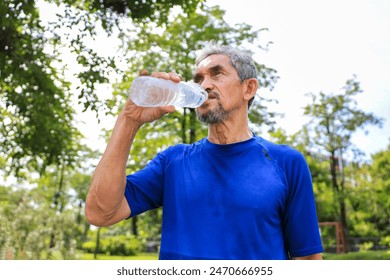 Senior Asian man is drinking water after morning exercise in the park for rehydration of sweat loss and healthy longevity lifestyle - Powered by Shutterstock