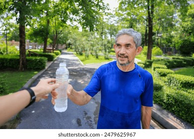 Senior Asian man is drinking water after morning exercise in the park for rehydration of sweat loss and healthy longevity lifestyle - Powered by Shutterstock