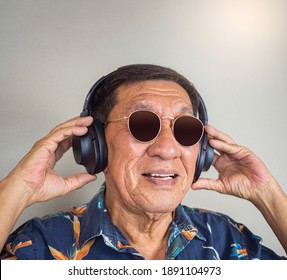 Senior Asian Man Listening To Music From Headphone Close Up