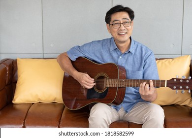 Senior Asian Man Playing Guitar At Home