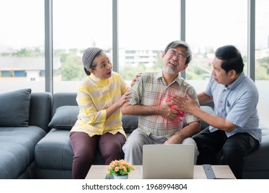 Senior Asian Man Sitting On Couch And Using Hand Touching To Chest From Having Heart Attack In Living Room With Elderly Friends To Help And Take Care. Old Male Heart Failure And Heart Attack In Home.