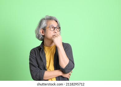 The senior Asian man with smart casual dressed standing against the light green background.
