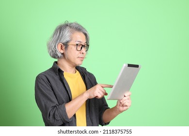 The Senior Asian Man With Smart Casual Dressed Standing Against The Light Green Background.