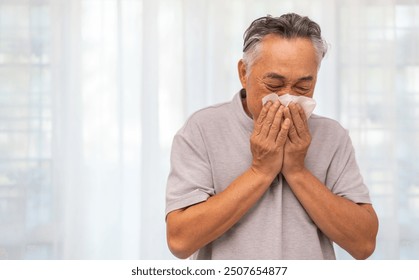 Senior asian man sneezing into a tissue, experiencing discomfort from cold or allergies, seasonal allergies, virus, flu and sick health, wellness, senior care, and medical treatment for respiratory	 - Powered by Shutterstock