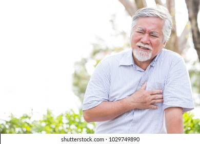 Senior asian Mann mit Brustschmerzen im Freien. Alter Mann, der die Brust hält mit schmerzhaftem Gefühl.