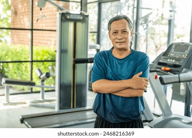 Senior asian man wearing sportswear warming up in fitness gym before exercise. Mature man stretching arm before running. Training athlete work out - Powered by Shutterstock