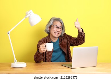 The Senior Asian Man Working On Laptop With Color Background.