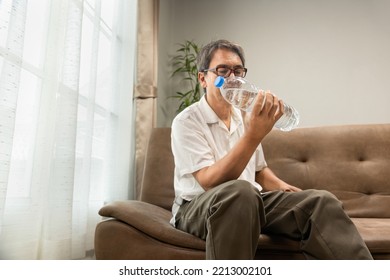 Senior Asian Man Workout Water Bottle At Home To Preserve His Muscle Mass, Prevent Sarcopenia And Bone Resorption.