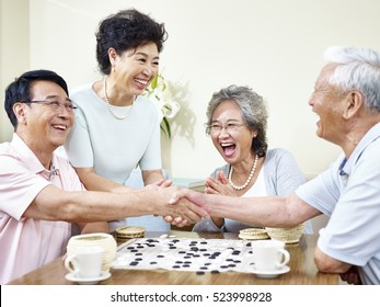 Senior Asian Men Shaking Hands  At The End Of A Weiqi Game.