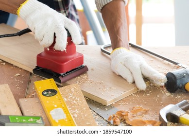 Senior Asian Old Man Carpenter Using Electric Wood Sanding Machine To Scrub Plank In Workshop