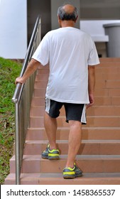 Senior Asian Old Man Walking Up Stairs In The Housing Estate. Retirement And Health Concept.