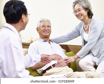 Senior Asian Patient Being Taken Care Of By His Wife And A Family Doctor
