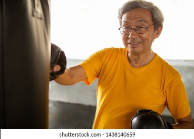 Senior Asian Sport Man In  Boxing Gloves Punching Bag  In Fitness Gym . Elder Male Exercising , Workout, Training ,healthy ,Retirement ,older, 