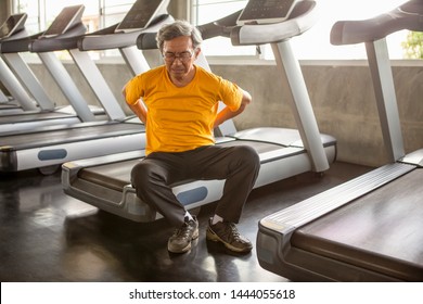 Senior Asian Sport Man Injury Back Pain  Sitting On Treadmill In Fitness Gym . Elder Male Exercising , Workout, Training ,healthy ,Retirement ,older, With Copy Space