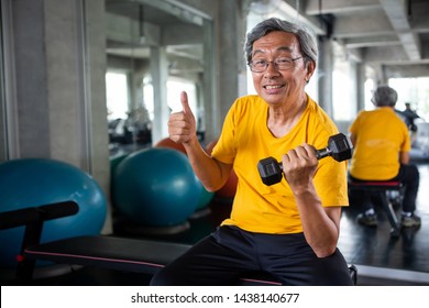 Senior Asian Sport Man Lifting Dumbbells And Show Thumbs Up In Fitness Gym . Elder Male Exercising ,  Working Out , Training Weights, Healthy ,Retirement , Older, Looking Camera 