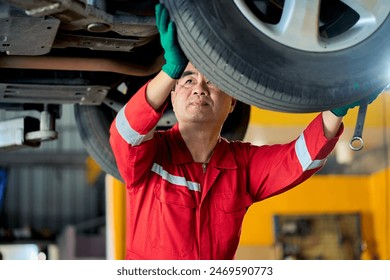 Senior asian technician male in red suit repair car wheel and tire when car on a lift power machine in car garage. - Powered by Shutterstock