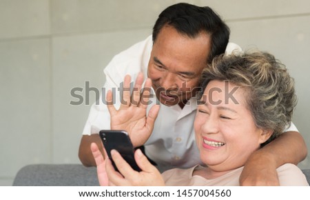 Senior Asian wife and husband use video call to son or daughter with happy smiling face. Warm family. Social distancing.