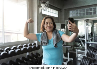 Senior Asian Woman Attractive Smiling Active Fitness In Gym And Taking A Selfie Showing Muscle.